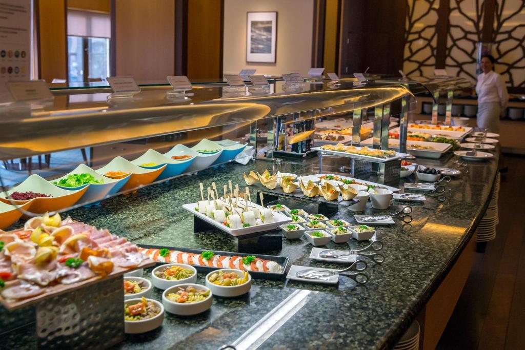 A long buffet line presents salads, cold dishes, dips, and prepared bites.