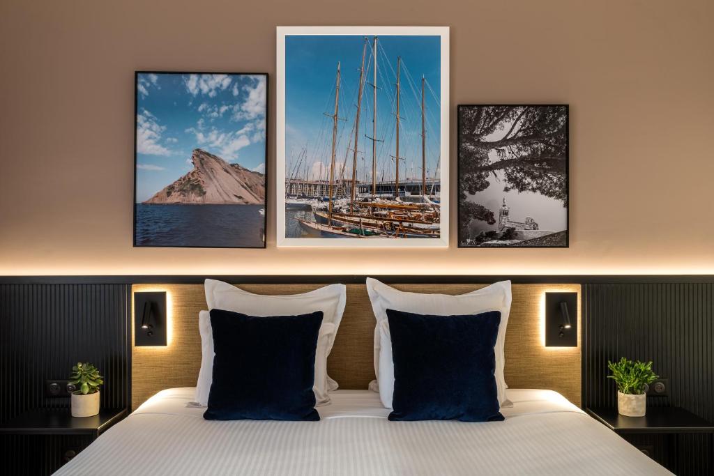 a bedroom with a bed with four paintings on the wall at Hôtel Villa M Marseille in Marseille