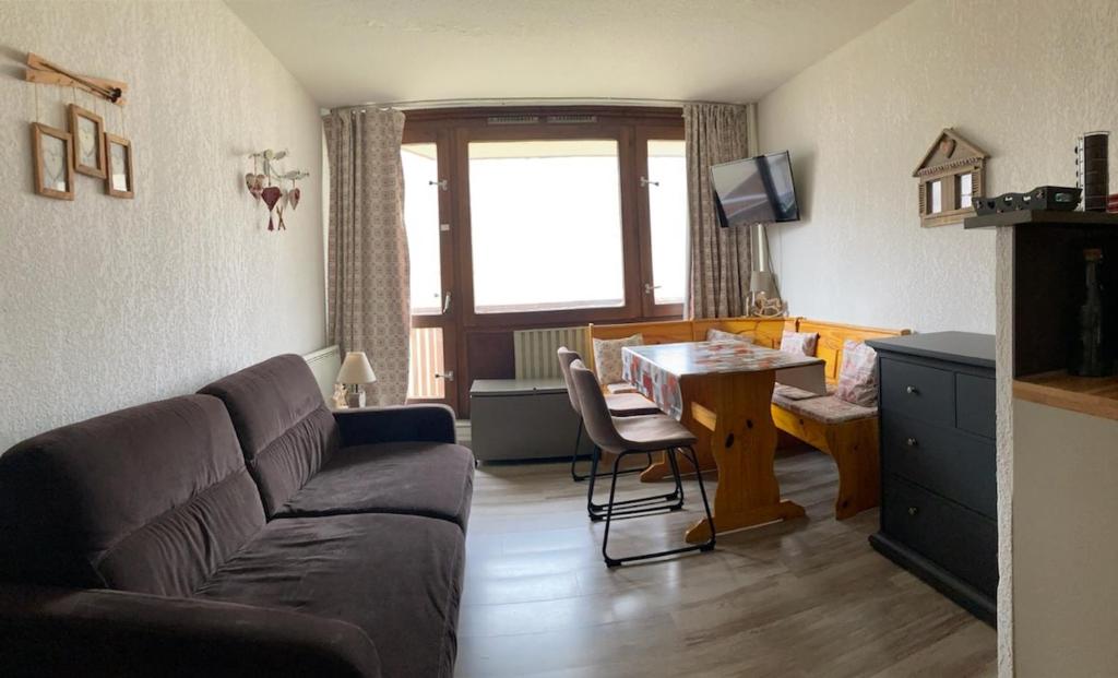 een woonkamer met een bank, een tafel en een bureau bij Le Cocon Themnest in La Mongie