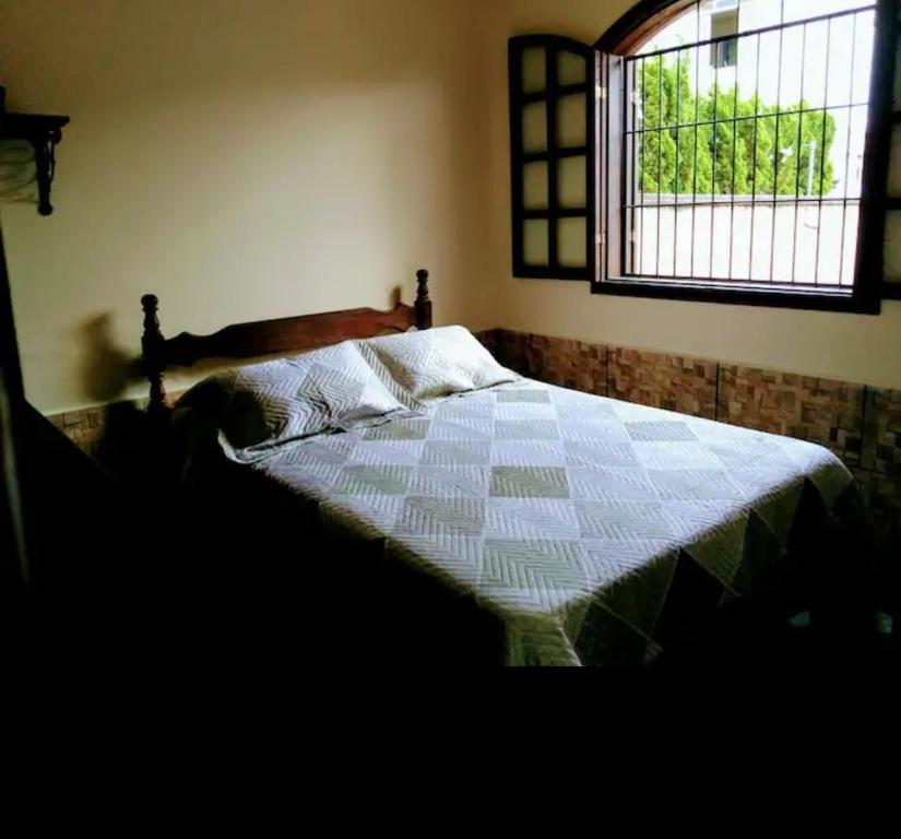 Imperdível - Casa aconchegante com varanda في أورو بريتو: غرفة نوم بسرير ولحاف ونافذة
