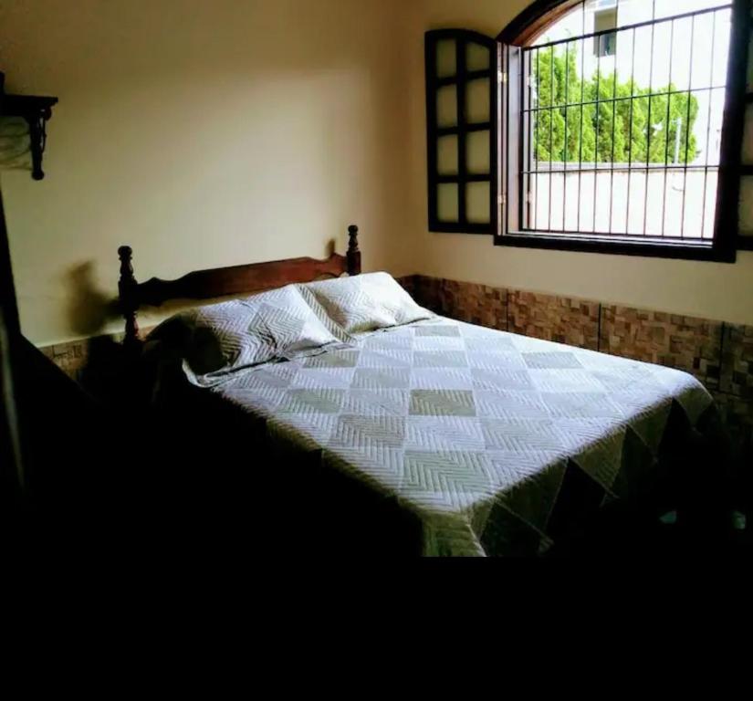 a bedroom with a bed with a quilt and a window at Imperdível - Casa aconchegante com varanda in Ouro Preto