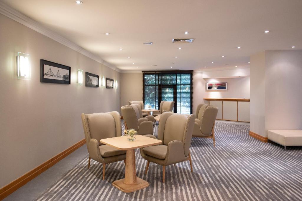 A quiet lounge offers upholstered chairs and small tables beside a reception counter.
