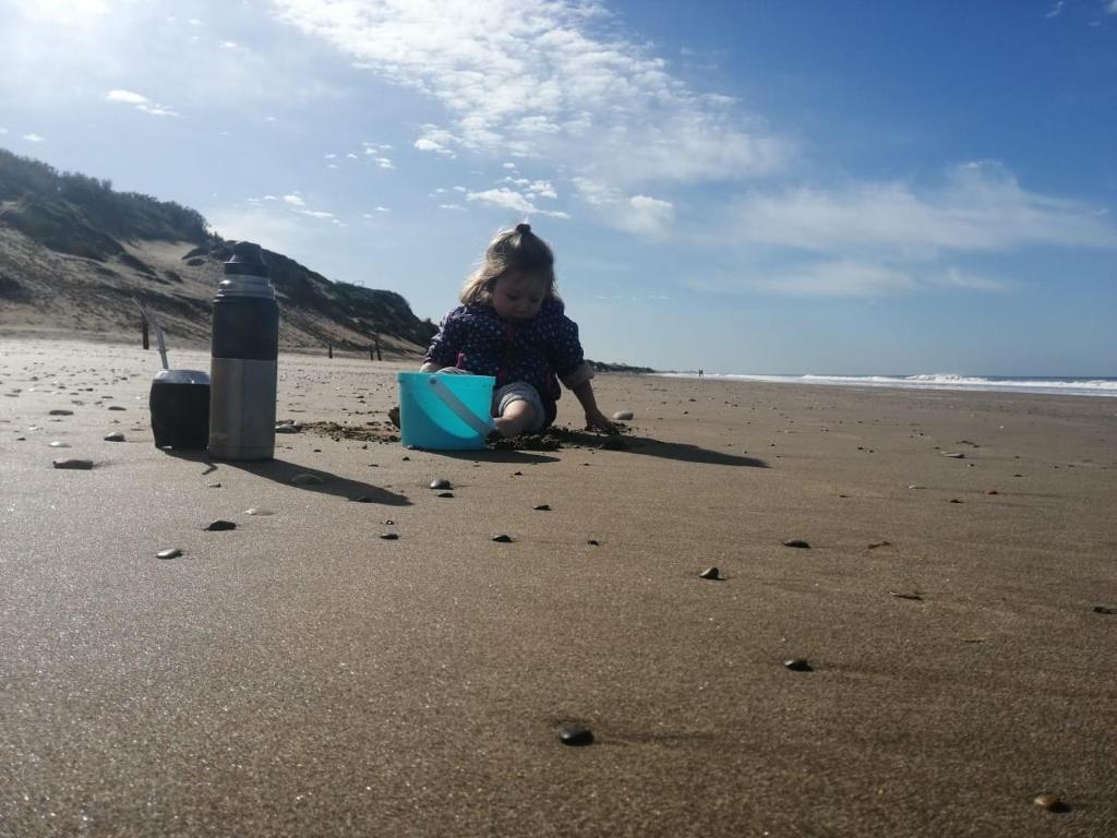 a little girl playing in the sand on the beach at Wenuray MdQ in Mar del Plata