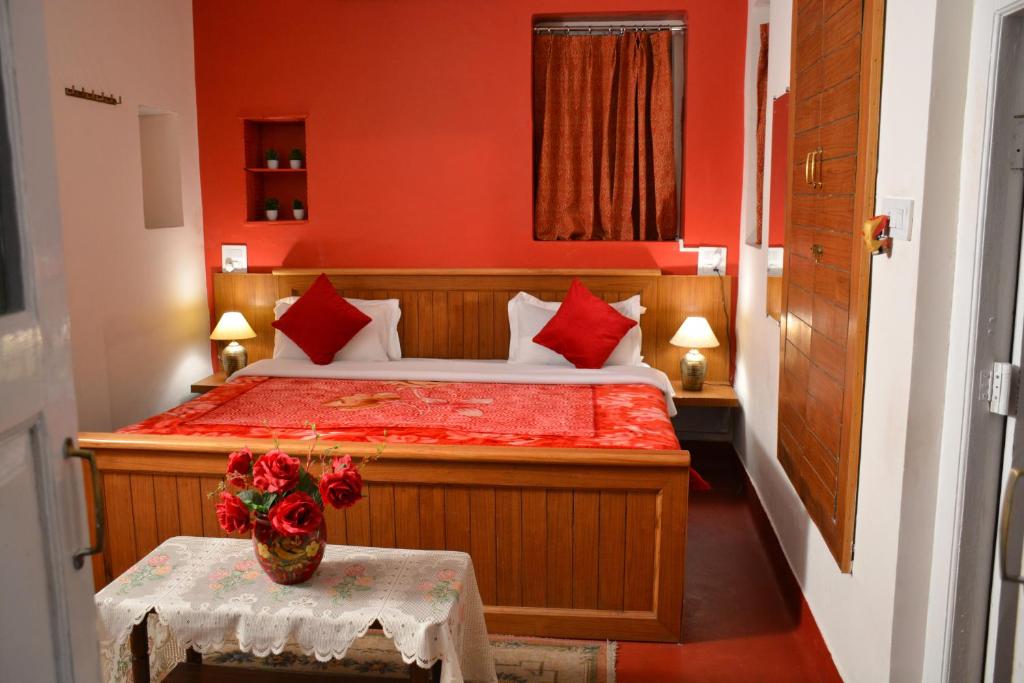a bedroom with a bed with red walls and a table at Solan Retreat in Solan