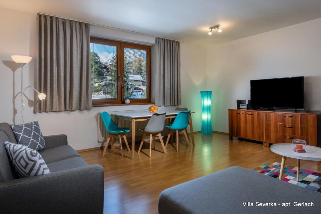 ein Wohnzimmer mit einem Sofa und einem Tisch mit Stühlen in der Unterkunft Apartmány Villa Severka in Nový Smokovec