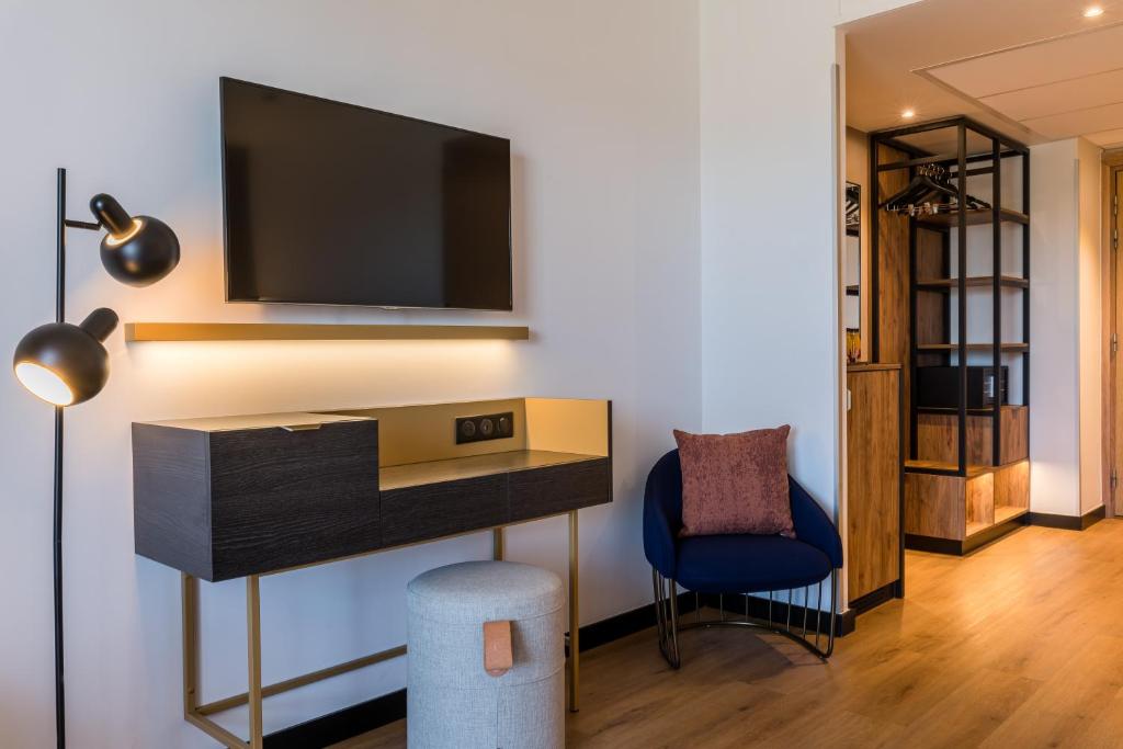 a living room with a tv and a blue chair at Hôtel Villa M Marseille in Marseille