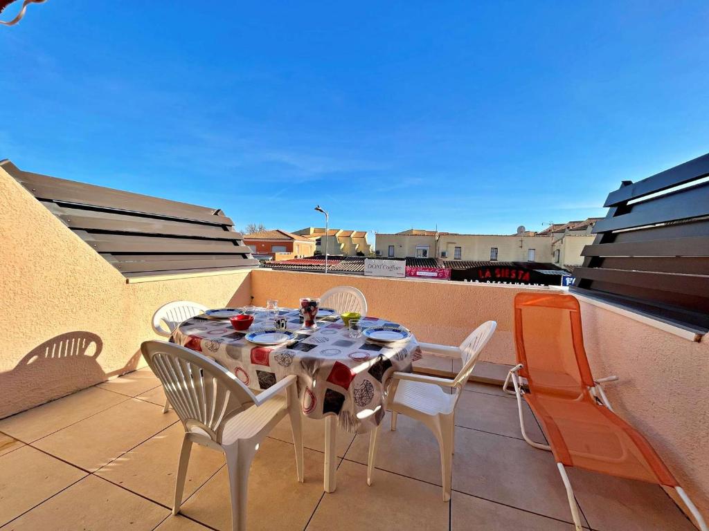 une table et des chaises assises sur un balcon dans l'établissement Appartement au centre de Marseillan avec terrasse et parking, proche commodités - FR-1-387-178, à Marseillan