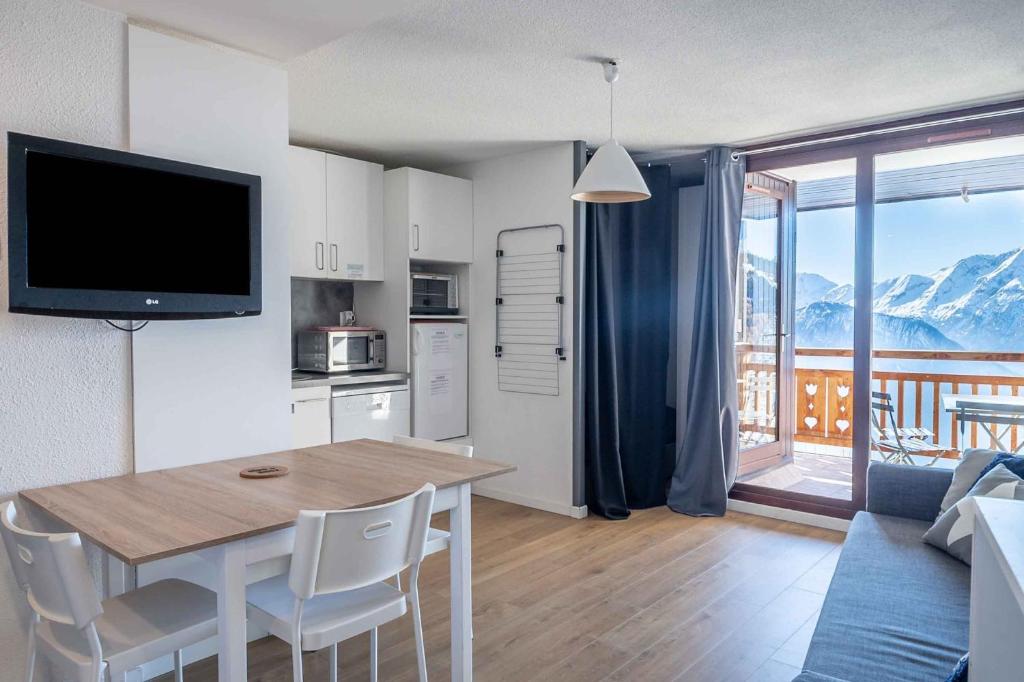 kuchnia i salon ze stołem i telewizorem w obiekcie Appartement d'une chambre avec terrasse amenagee a L'Alpe d'Huez w LʼAlpe-dʼHuez