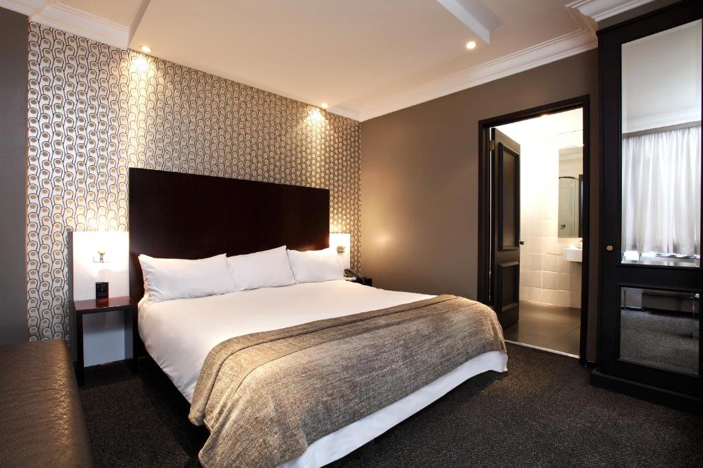 um quarto de hotel com uma cama grande e uma casa de banho em Manhattan Hotel em Pretoria