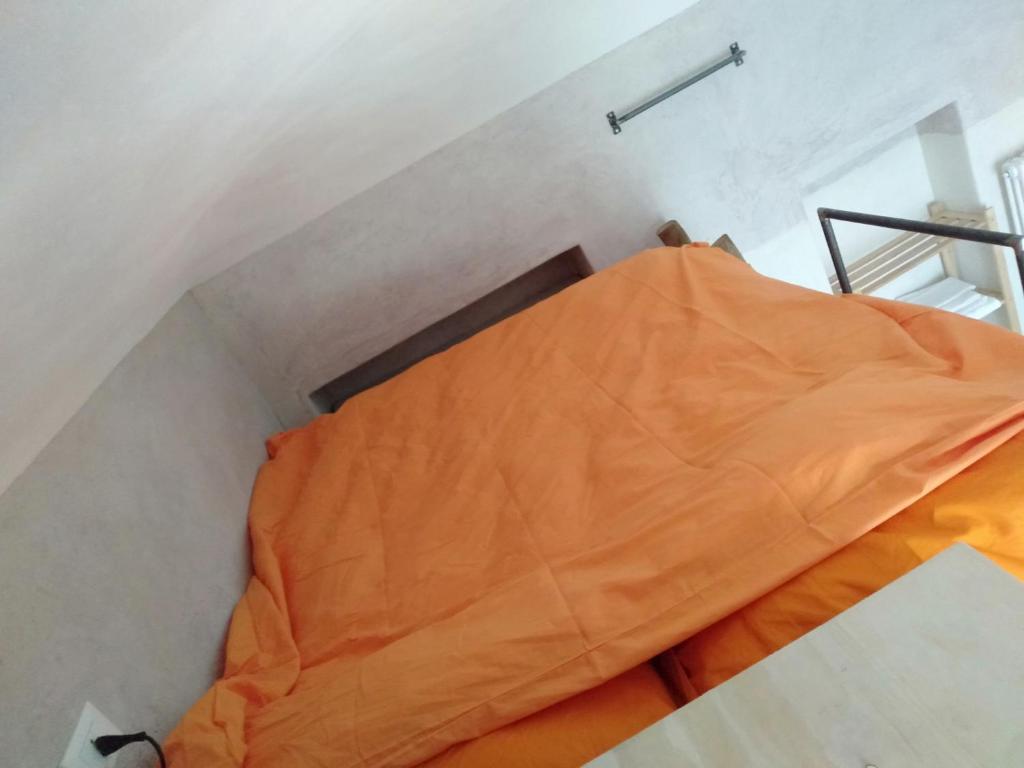 a bed in a room with an orange sheet at Marsò _ Piccolo rifugio cittadino in Turin