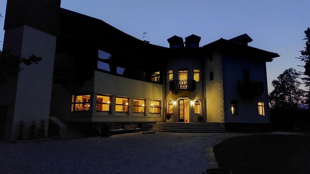 ein großes Haus mit nachts eingeschaltetem Licht in der Unterkunft B&B Villa Cavallier in Barzio