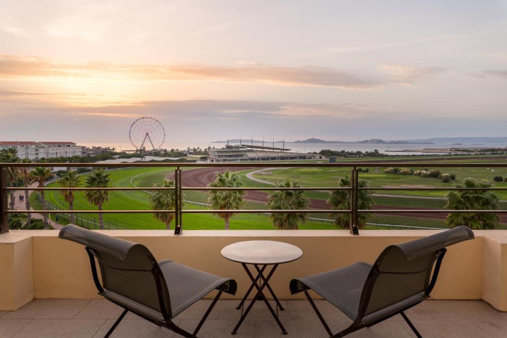 a balcony with chairs and a table and a golf course at Hôtel Villa M Marseille in Marseille