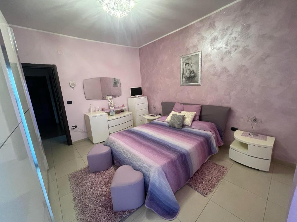 ein Schlafzimmer mit einem lila Bett und einer rosa Wand in der Unterkunft Antonella's House Pompei - Sorrento - Amalfi in Pompei