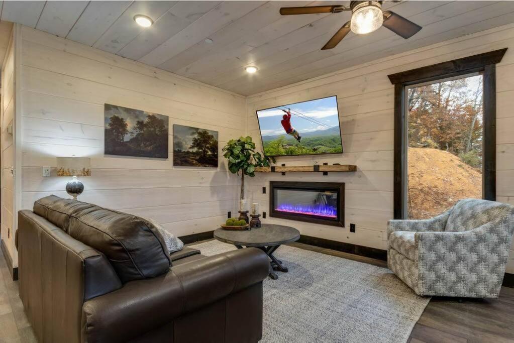a living room with a couch and a tv at Blue Moon Ridge: Brand NEW Cabin! 5 bedrooms, pool/hot tub, theatre in Pigeon Forge