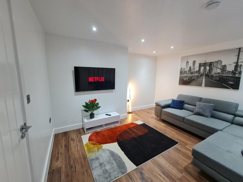 a living room with a couch and a tv on a wall at Elm Park Cheerful 4-Bedroom Holiday Home in Hornchurch