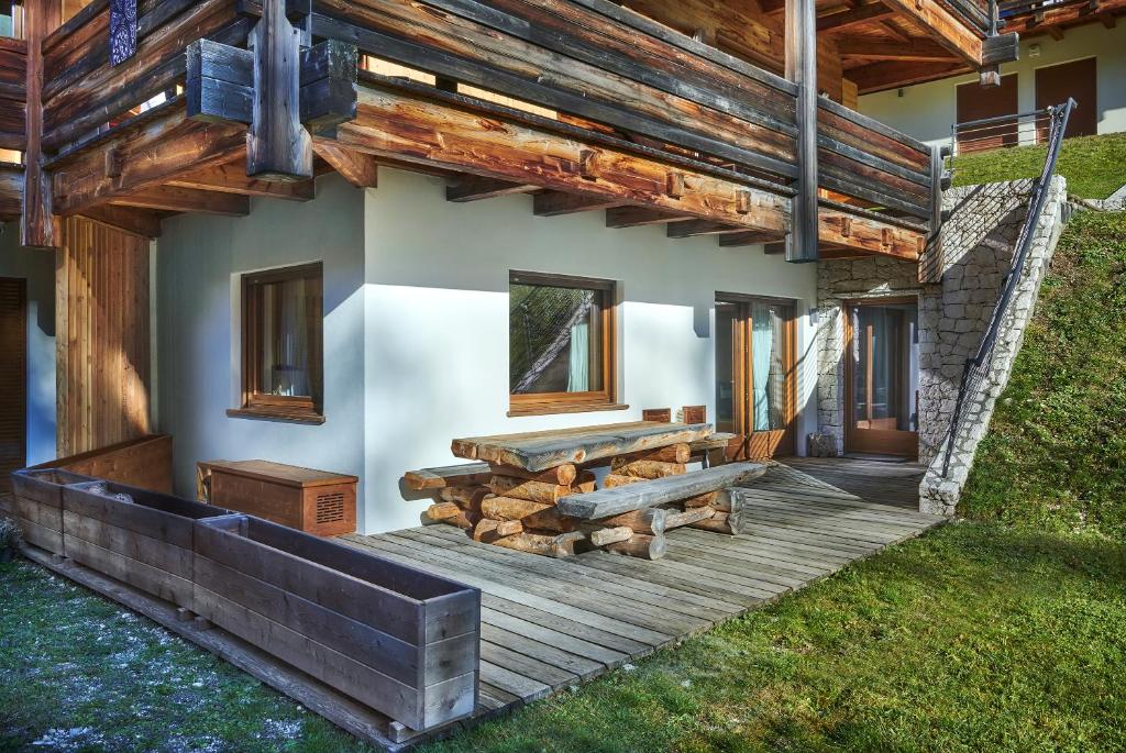 una casa con una terraza de madera con una pila de troncos en The Wooden House Cortina, en Cortina dʼAmpezzo