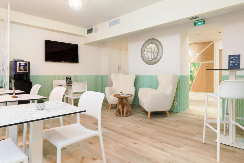 a waiting room with white chairs and tables at Hotel Florence Nice in Nice