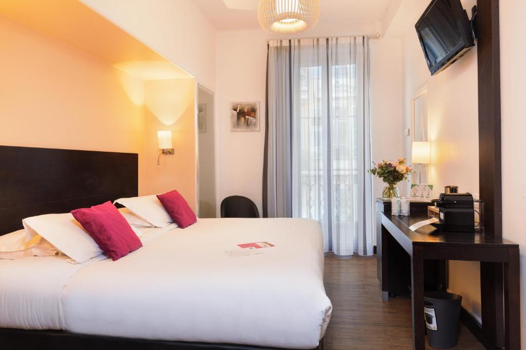 a hotel room with a large bed and a desk at Hotel Florence Nice in Nice