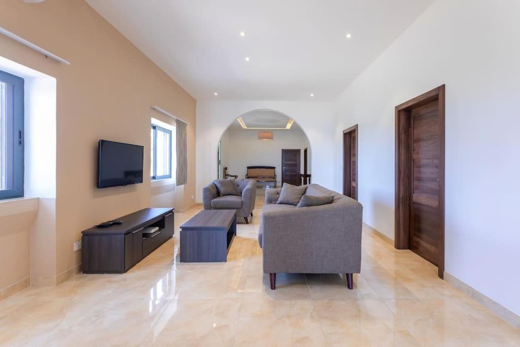 a living room with couches and a flat screen tv at Spacious, Bright, Valley & Sea View Maisonette in Xagħra