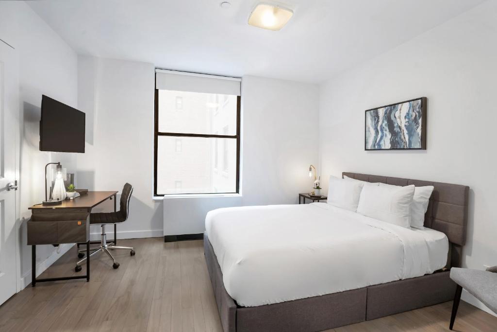 a bedroom with a bed and a desk with a computer at National at 888 Sixth Avenue - Furnished Apartments in New York
