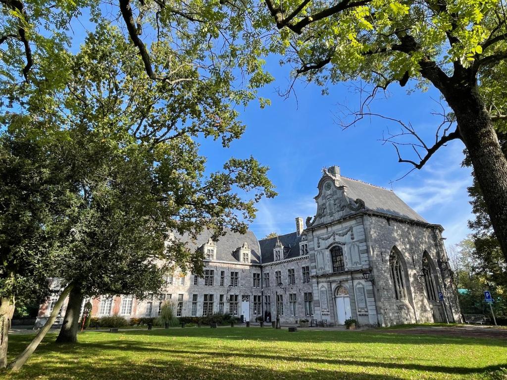 un antiguo edificio con árboles en primer plano en Suite Royale Hotel Ferme Du Château Fontaine en Fontaine-lʼÉvêque