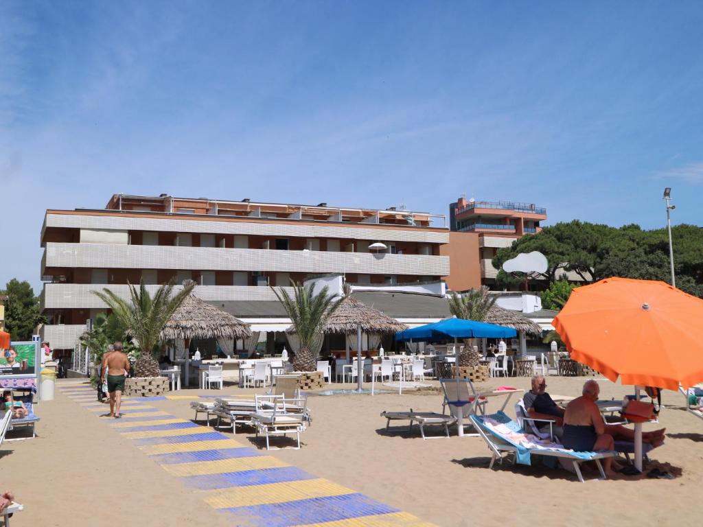una spiaggia con sedie e ombrelloni e un edificio di Casa Al Mare a Lignano Sabbiadoro