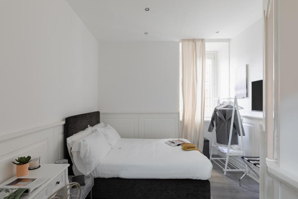 a white bedroom with a bed and a desk at Relais Roma Centro in Rome