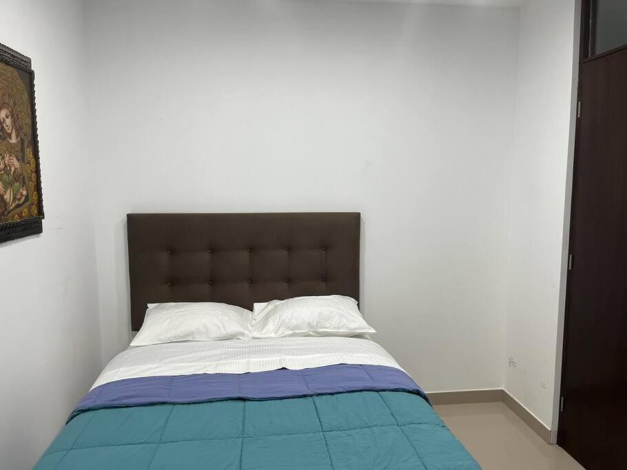 a bedroom with a bed with a blue and white blanket at Apartamento en Ica 3 in Ica