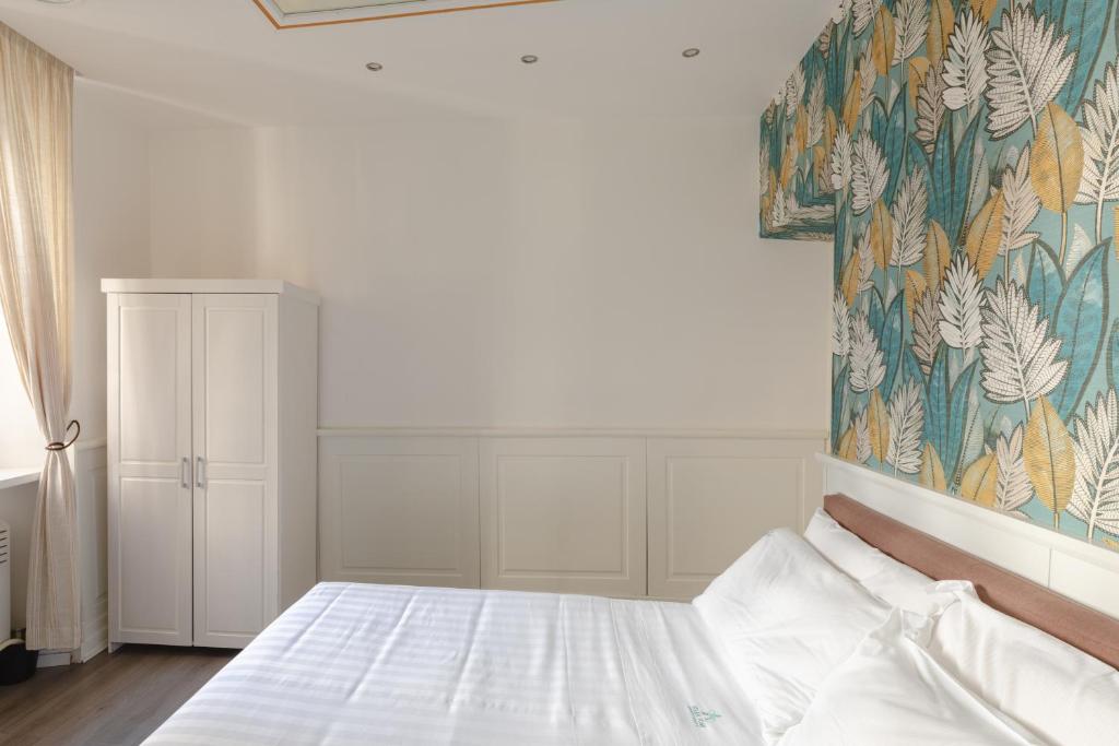 a bedroom with a white bed with a floral wallpaper at Relais Roma Centro in Rome