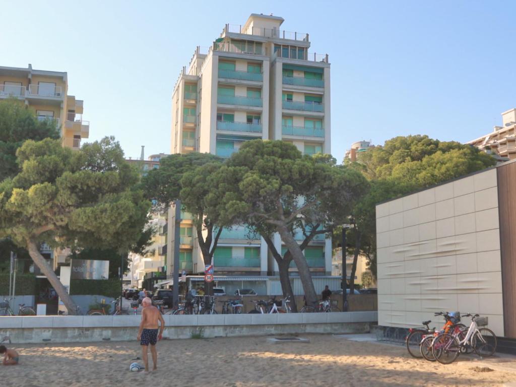mężczyzna stojący na plaży przed budynkiem w obiekcie Occidente w Lignano Sabbiadoro