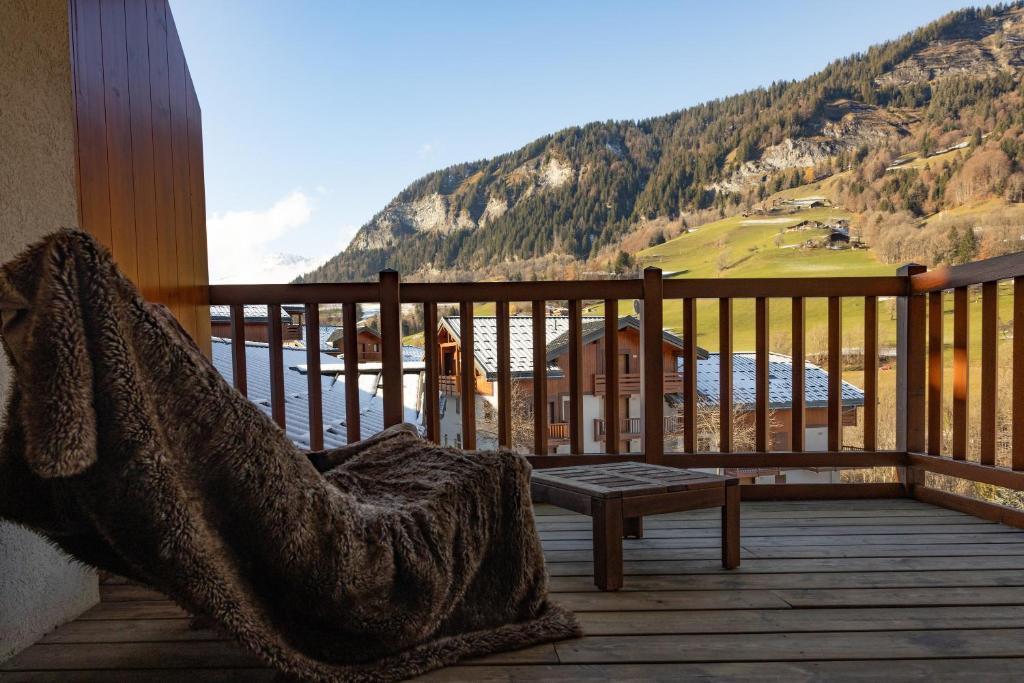 uma varanda com um banco e vista para uma montanha em 12 mn Megeve studio confort em Flumet