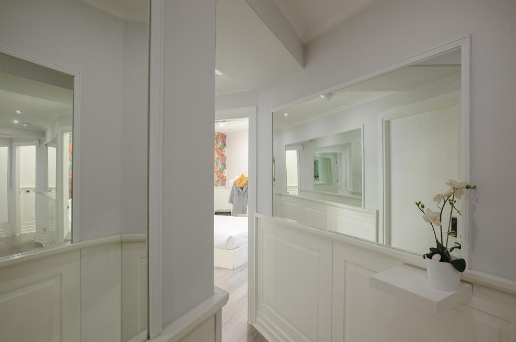 a bathroom with white walls and a large mirror at Relais Roma Centro in Rome