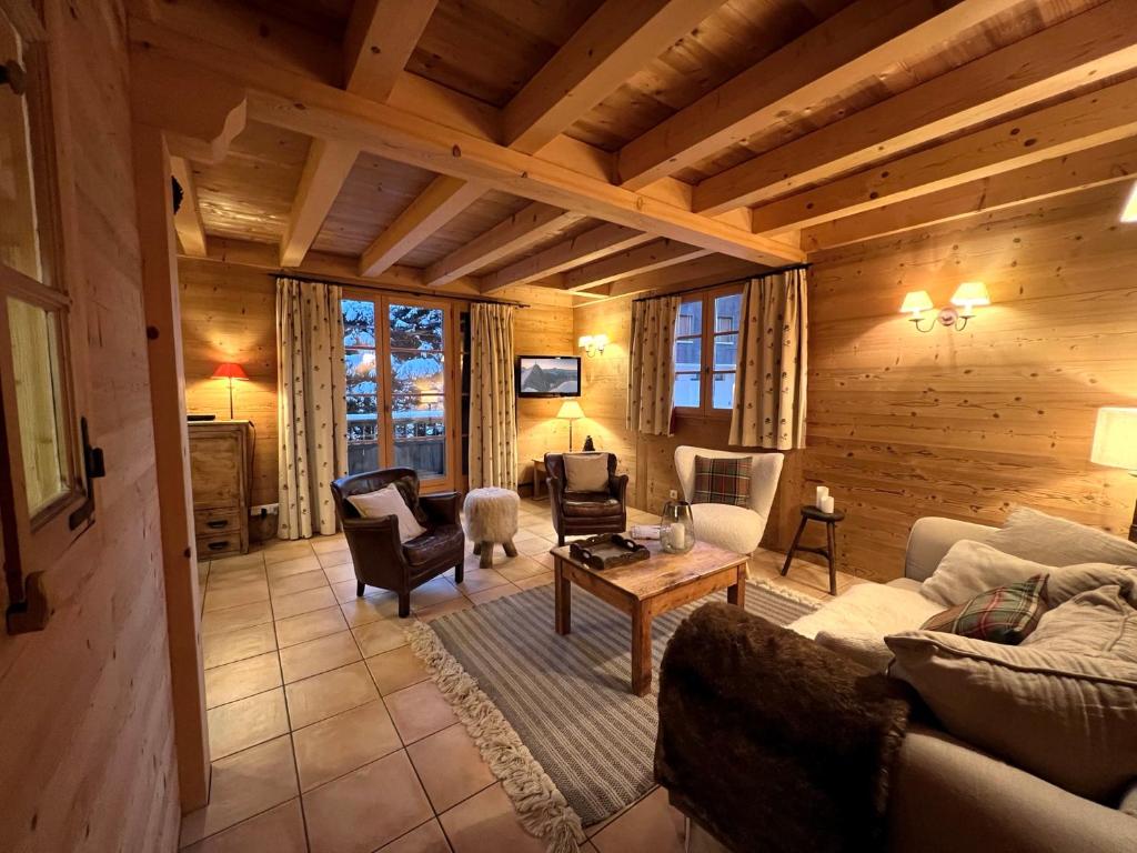 - un salon dans une cabane en rondins avec un canapé et des chaises dans l'établissement PATURAGE Demi chalet 4 chambres, à La Clusaz