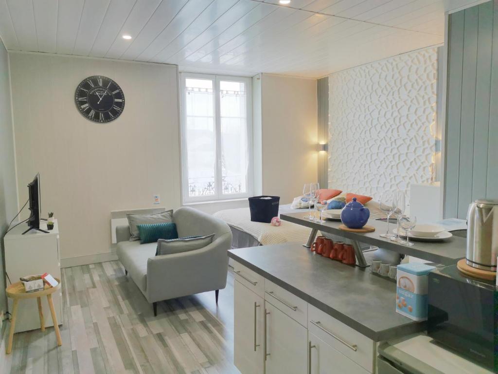 cocina y sala de estar con reloj en la pared en VITTEL LOC'S - LE 216, classé 3 étoiles proche des Thermes et tous commerces, en Vittel