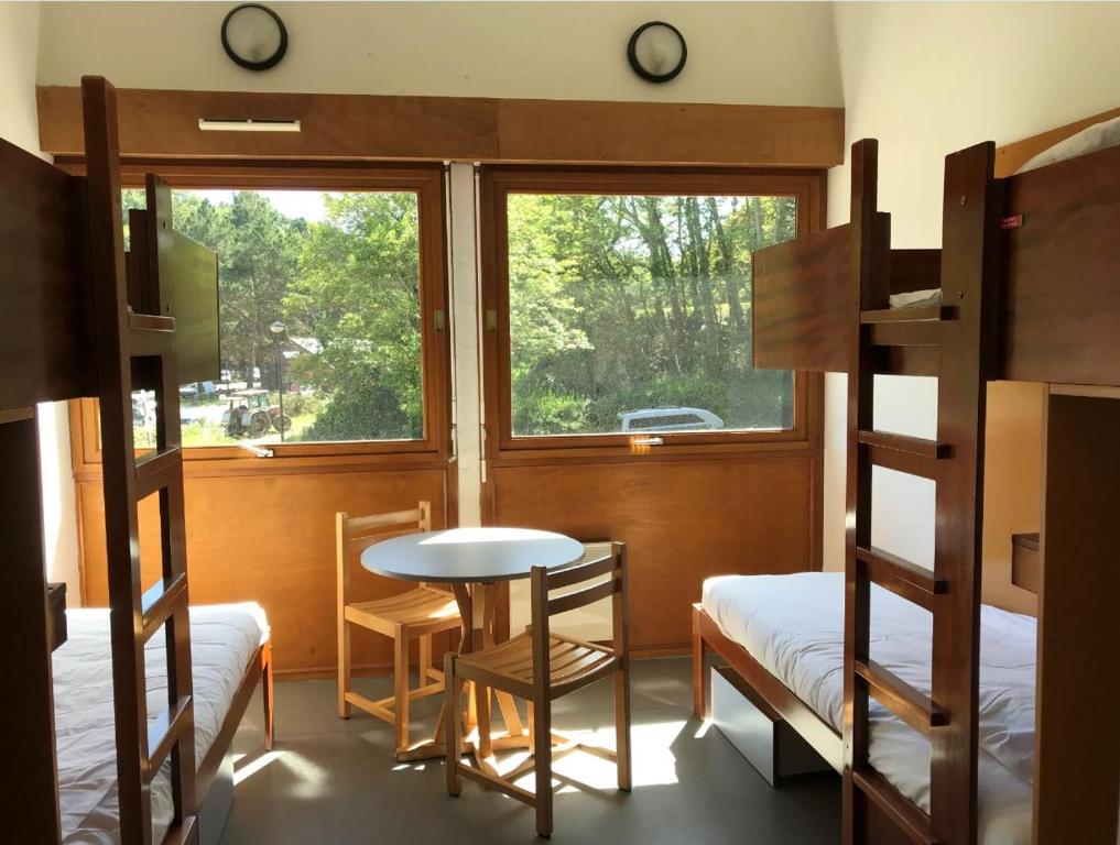 Zimmer mit Etagenbetten, einem Tisch und einem Fenster in der Unterkunft Auberge de Jeunesse HI Cancale in Cancale