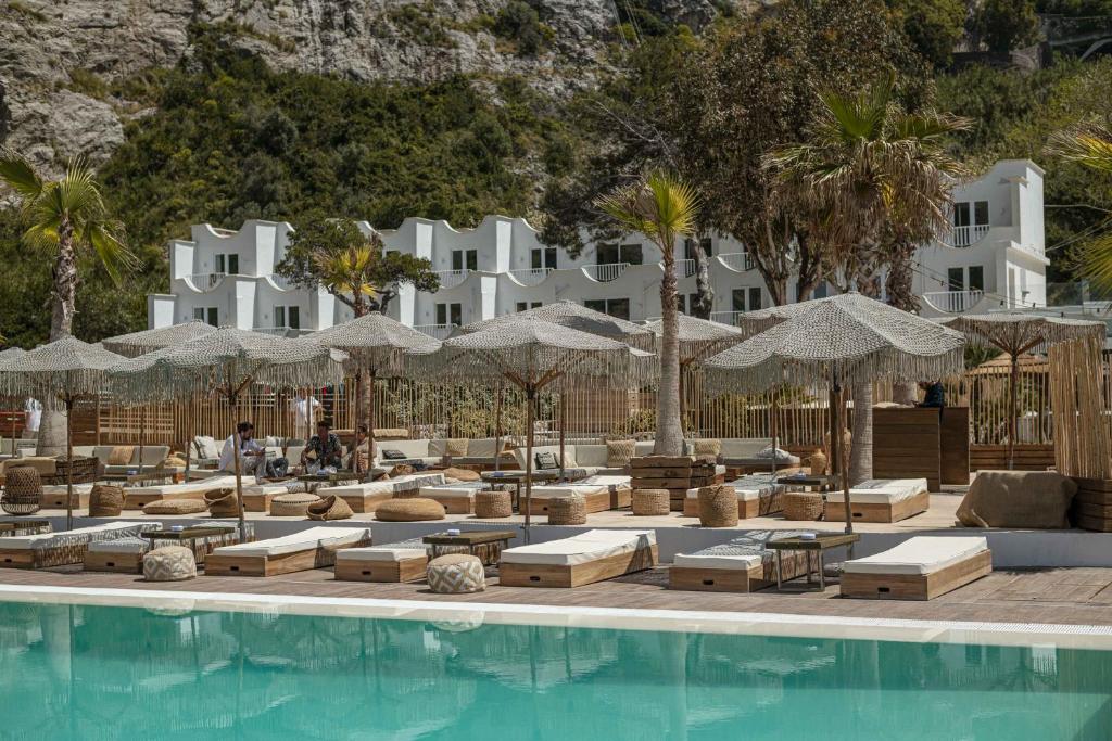 a resort with a pool with lounge chairs and umbrellas at Maya Beach Resort in Massa Lubrense