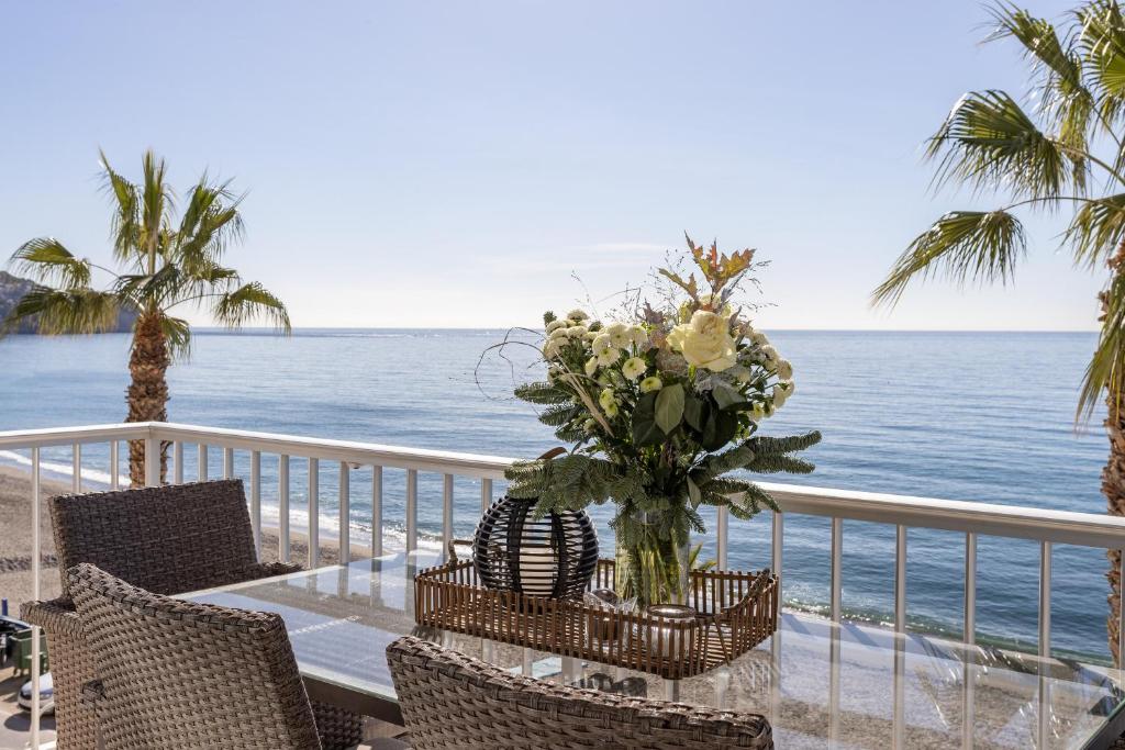 een tafel met een vaas met bloemen op het strand bij Modern luxury beach Penthouse in La Herradura