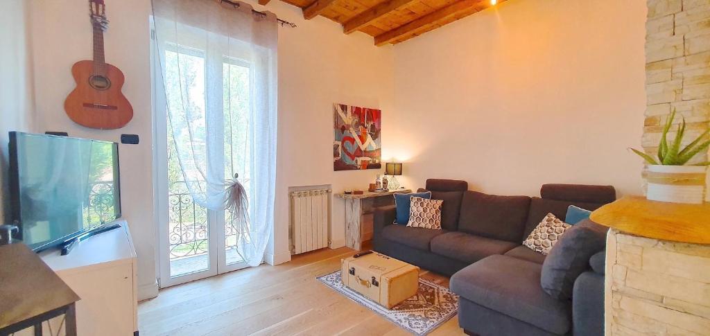sala de estar con sofá, TV y guitarra en Casa Valle Parco Lambro, en Albiate