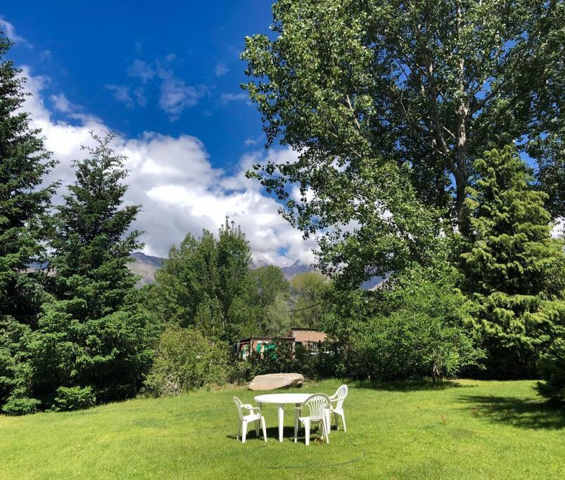 una mesa y sillas en un campo con árboles en Casa de montaña en un lugar mágico en Potrerillos