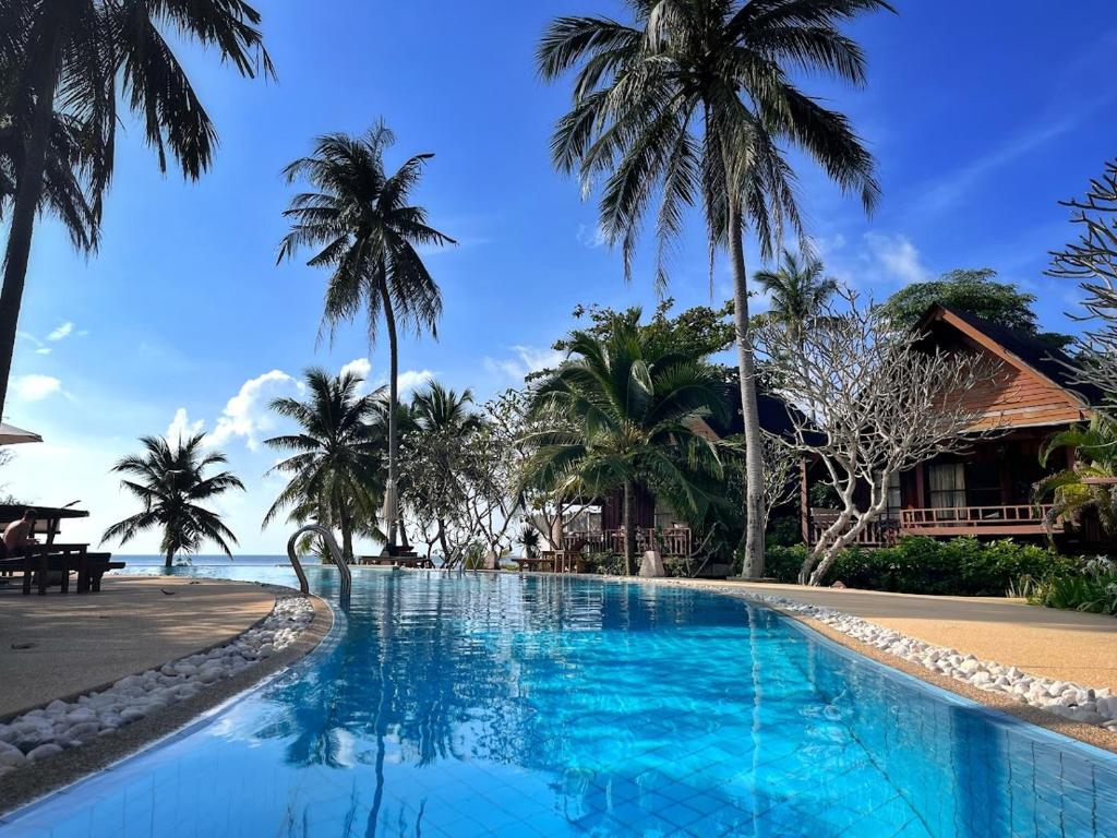 einen Pool neben einem Strand mit Palmen in der Unterkunft Green Papaya Beach Resort, Koh Phangan in Salad Beach