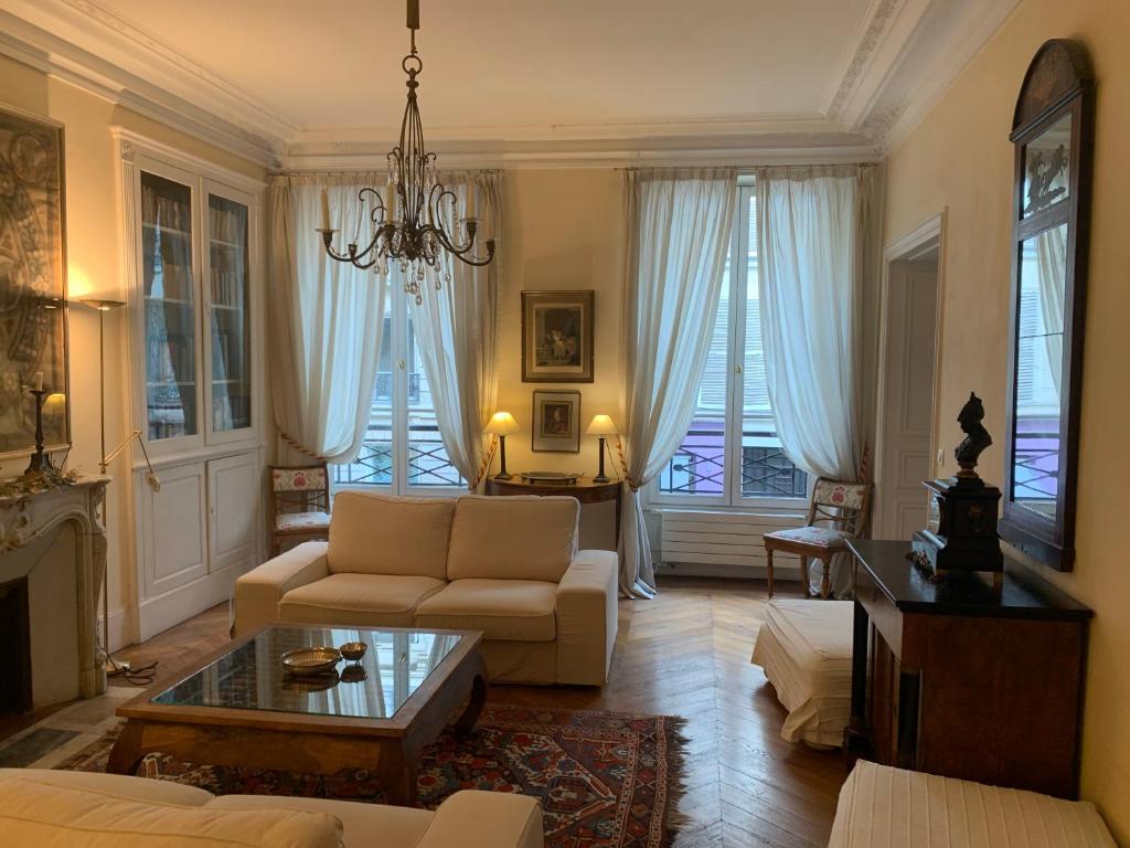 een woonkamer met een bank en een kroonluchter bij Appartement Artois in Parijs