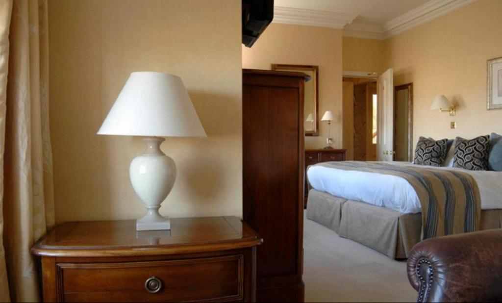 a bedroom with a bed and a lamp on a table at Wentworth Hotel in Aldeburgh