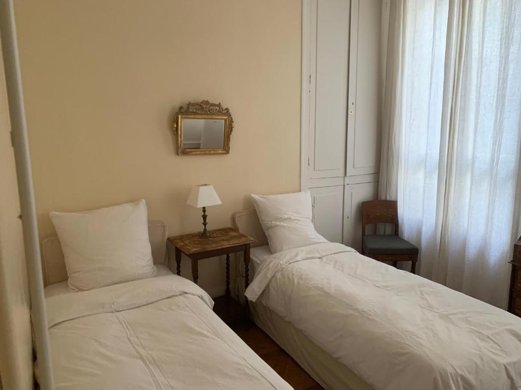 a bedroom with two beds and a table with a mirror at Appartement Artois in Paris