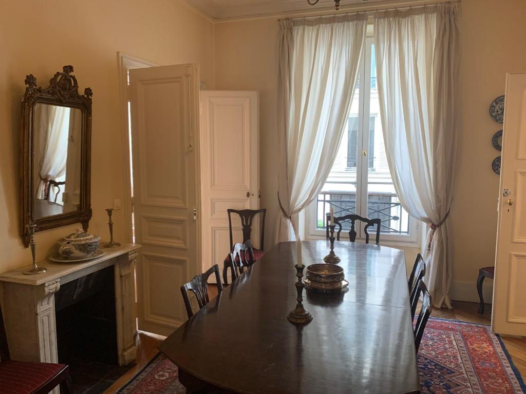 a dining room with a table and chairs and a mirror at Appartement Artois in Paris