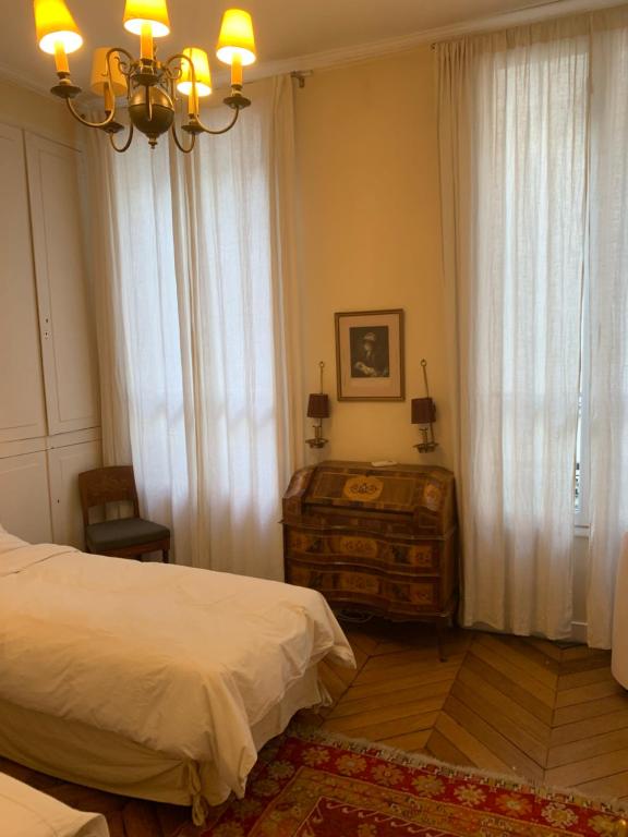 a bedroom with a bed and a dresser and curtains at Appartement Artois in Paris