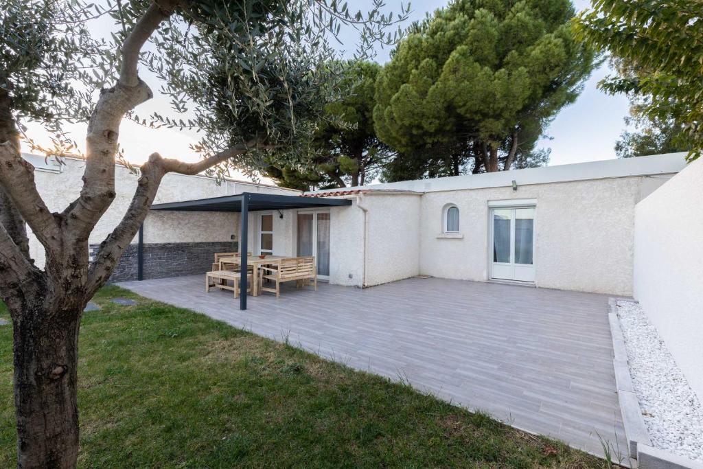 a patio with a picnic table next to a building at Maison Cosy - Plage 5min - Parc Expo- Arena-Centre ville in Mauguio