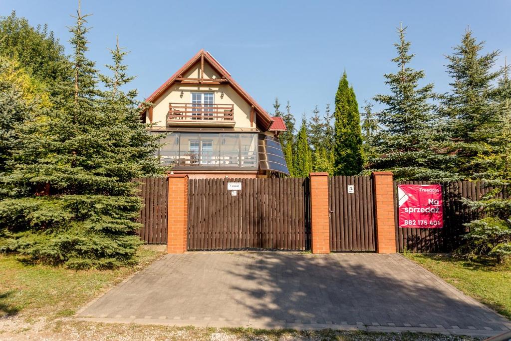 een huis met een houten hek en een hek bij Domek nad jeziorem in SzczybaÅ‚y OrÅ‚owskie