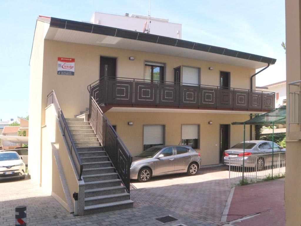 un edificio con una escalera y coches estacionados frente a él en Viviana, en Lignano Sabbiadoro