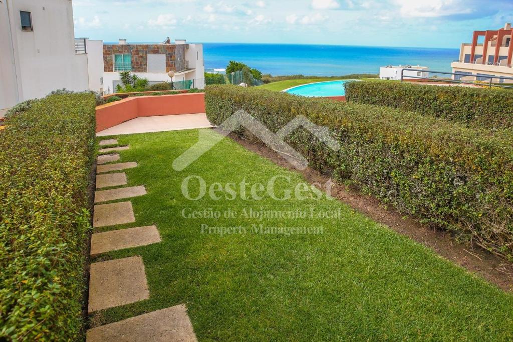un jardín con un seto y una piscina en Casa Menezes en Lourinhã
