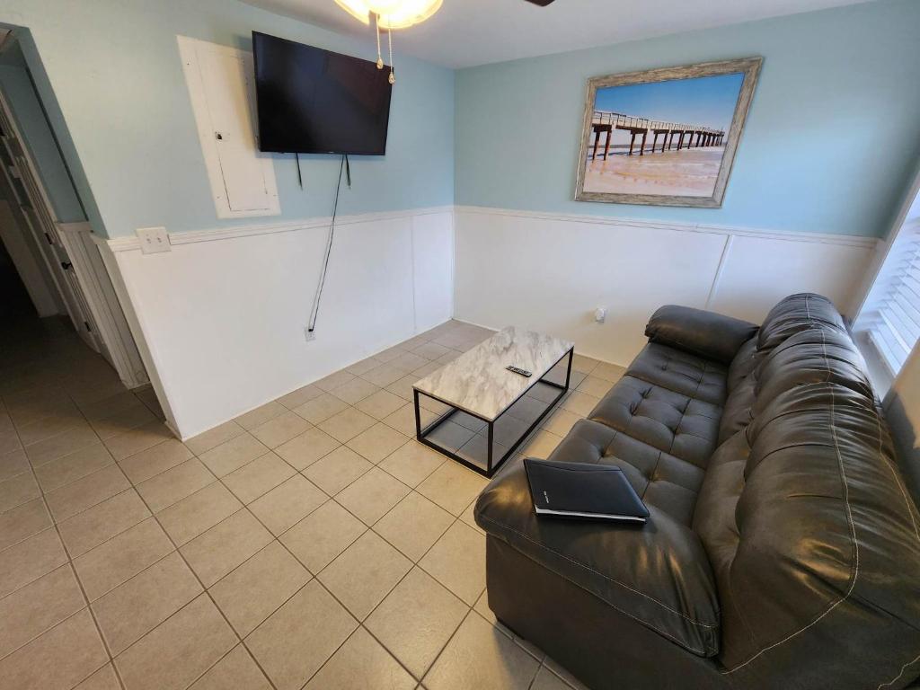 uma sala de estar com um sofá de couro e uma televisão em 125 Atlantic Avenue Unit F - Pet Friendly! Walk To The Beach and Pier! 1BR -1BA - Sleeps 2-4 guests! em Myrtle Beach